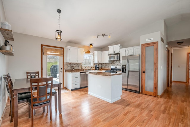 kitchen featuring backsplash, white cabinetry, stainless steel appliances, light wood finished floors, and lofted ceiling