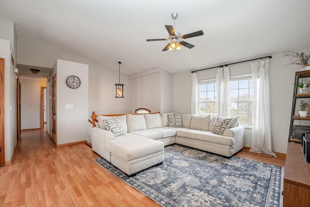 living room featuring light wood-style flooring, lofted ceiling, baseboards, and ceiling fan