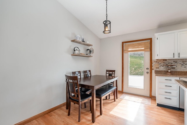 dining room featuring light wood-type flooring, baseboards, and vaulted ceiling