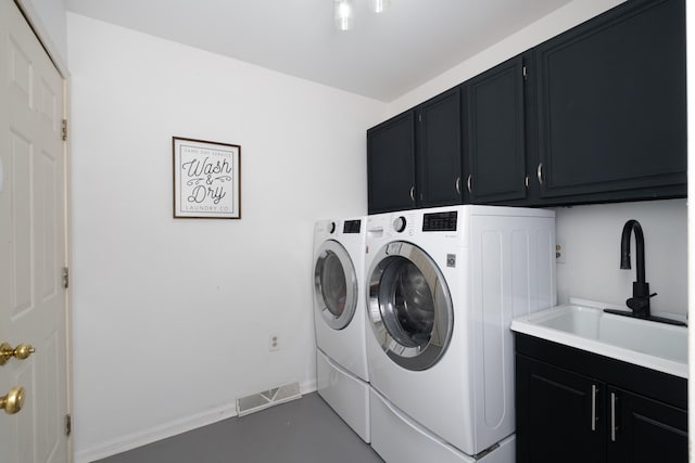 washroom with a sink, visible vents, cabinet space, and washer and clothes dryer