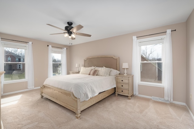 bedroom featuring a ceiling fan, visible vents, light colored carpet, and baseboards