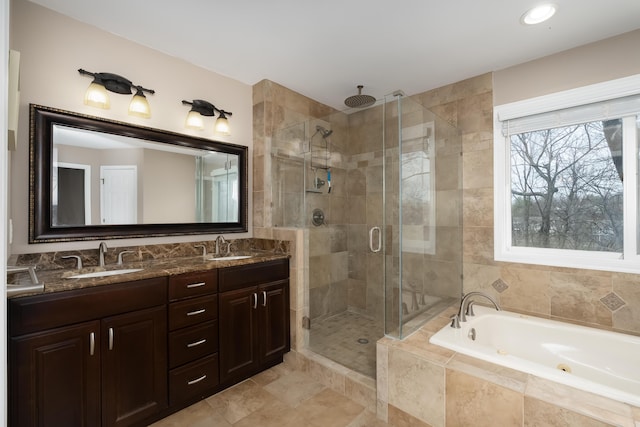 full bathroom featuring double vanity, a jetted tub, a stall shower, and a sink