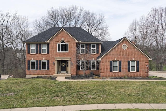 colonial inspired home featuring a front lawn, brick siding, and a chimney