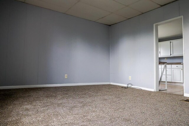 spare room with light colored carpet, baseboards, and a drop ceiling