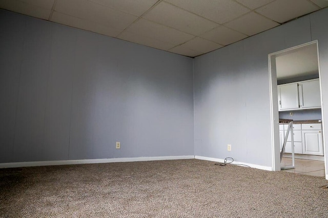 unfurnished room featuring baseboards, a paneled ceiling, and light colored carpet