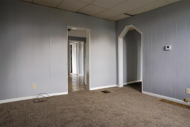 unfurnished room with baseboards, visible vents, carpet floors, arched walkways, and a paneled ceiling