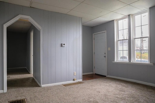 empty room featuring a drop ceiling, baseboards, carpet, and visible vents
