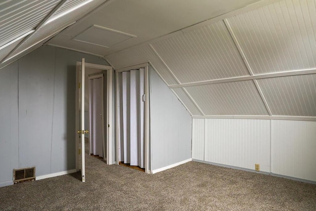 additional living space featuring visible vents, attic access, carpet, and lofted ceiling