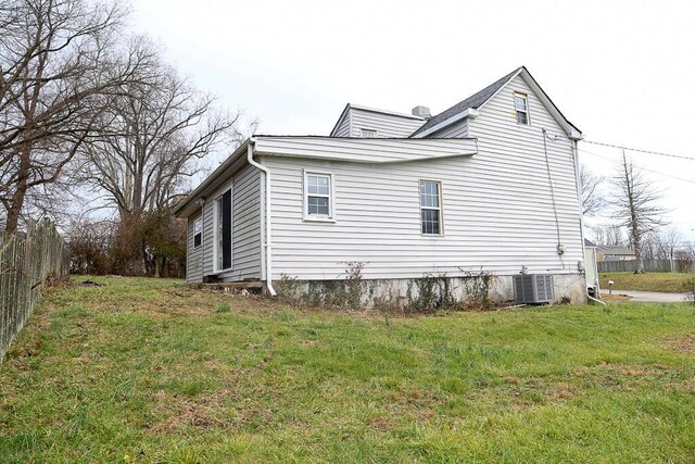 view of side of property featuring cooling unit, a yard, and fence