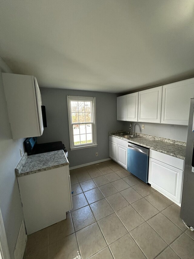 kitchen featuring a sink, white cabinetry, appliances with stainless steel finishes, light tile patterned floors, and baseboards