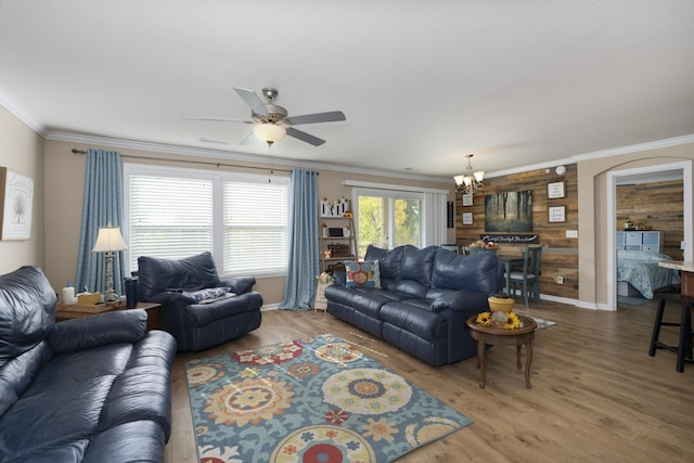 living room featuring ornamental molding, ceiling fan with notable chandelier, wood finished floors, arched walkways, and baseboards