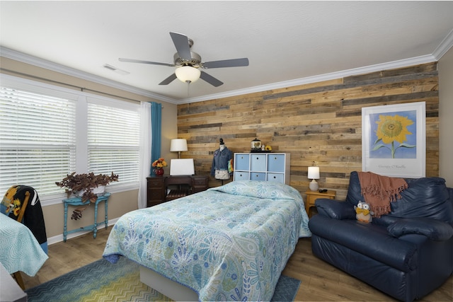 bedroom featuring a ceiling fan, wood finished floors, visible vents, baseboards, and crown molding