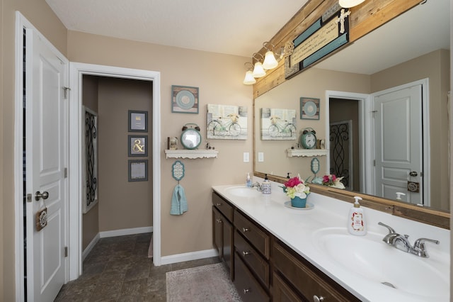 bathroom with double vanity, baseboards, and a sink