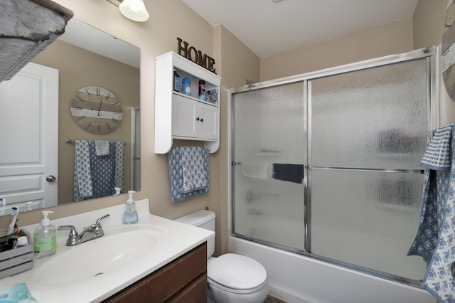 bathroom with toilet, vanity, and bath / shower combo with glass door