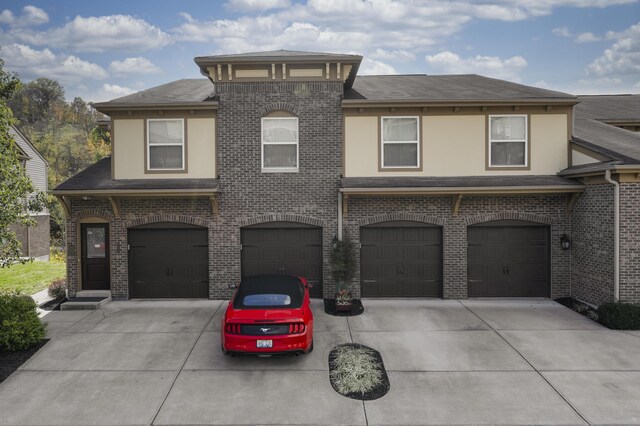 view of front of home with brick siding, an attached garage, and driveway