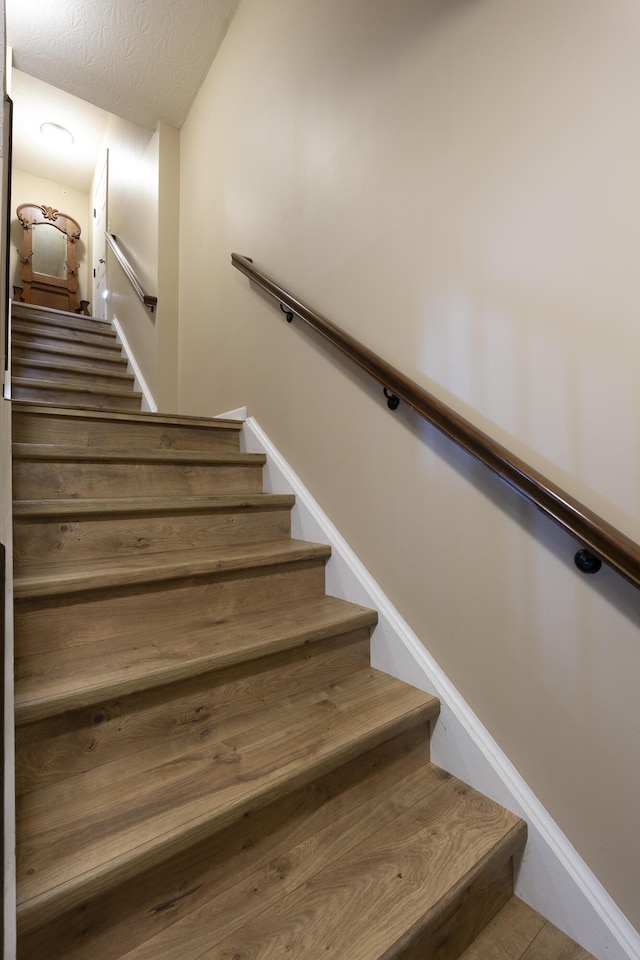 stairs featuring baseboards and a textured ceiling