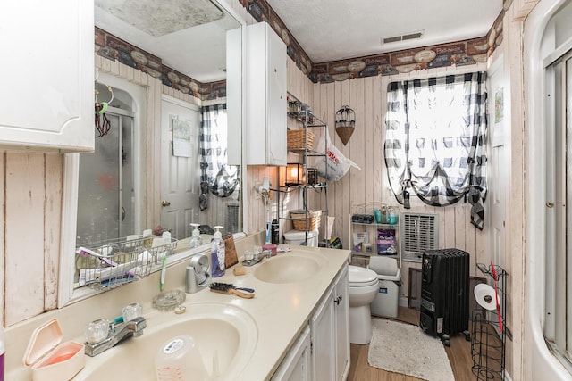 full bathroom featuring toilet, a sink, double vanity, and visible vents