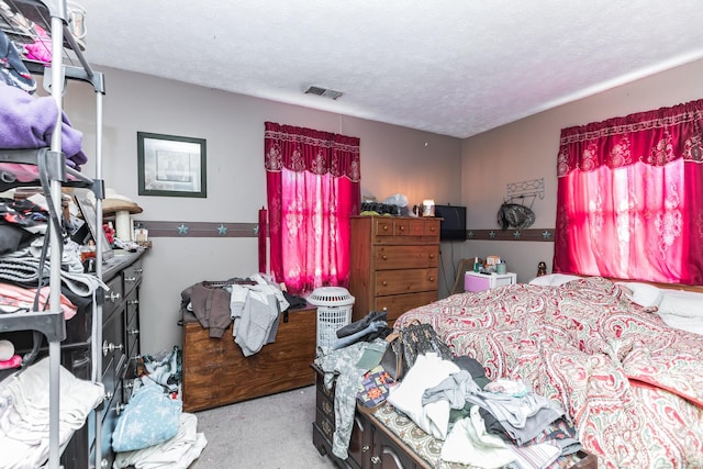 carpeted bedroom featuring a textured ceiling and visible vents
