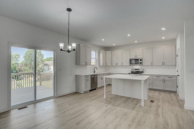 350 Foxhunt Dr, Walton, KY 41094 - kitchen with stainless steel appliances, light wood-style flooring, light countertops, backsplash, and a chandelier