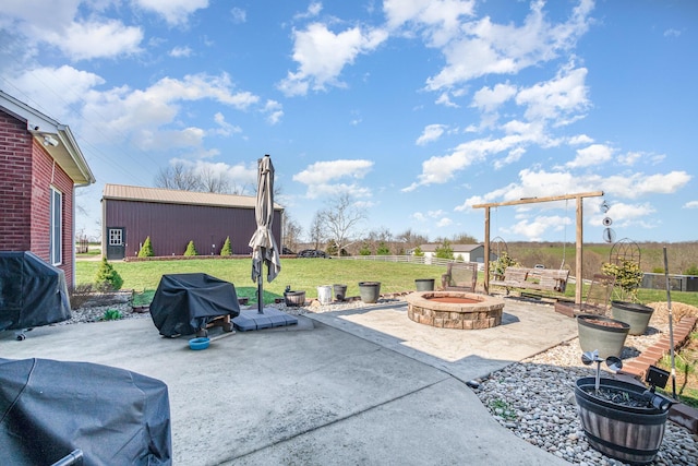 view of patio / terrace featuring a grill, a fire pit, fence, and an outbuilding