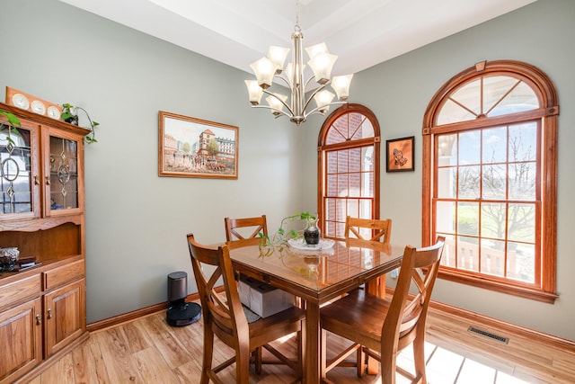 dining area with baseboards, visible vents, light wood-style flooring, and a chandelier