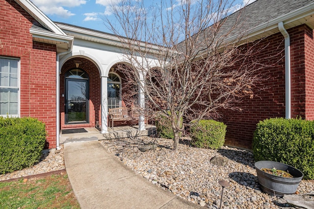 doorway to property with brick siding and a porch