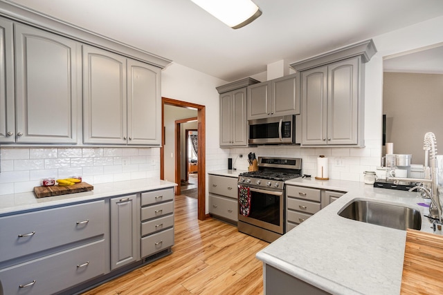 kitchen featuring a sink, stainless steel appliances, gray cabinets, and light wood finished floors