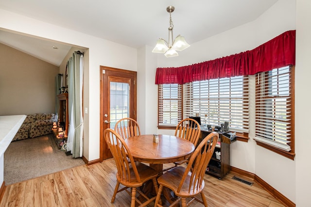 dining space featuring baseboards, visible vents, light wood-type flooring, and an inviting chandelier