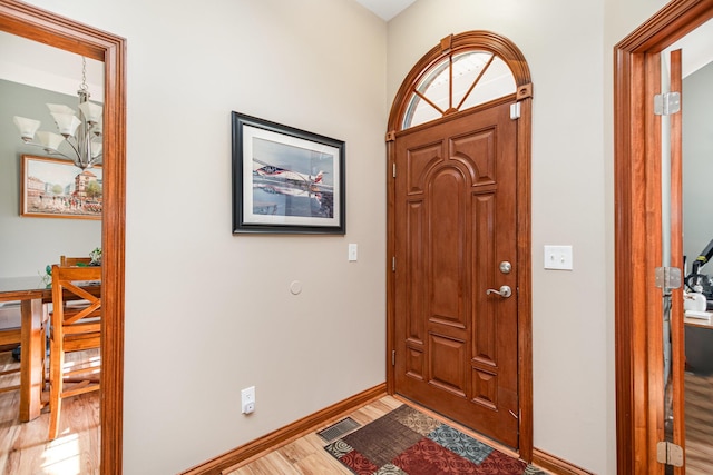 entryway with baseboards, a notable chandelier, visible vents, and wood finished floors