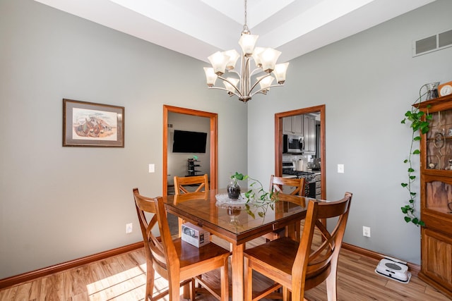 dining area with baseboards, visible vents, light wood-style flooring, and a chandelier