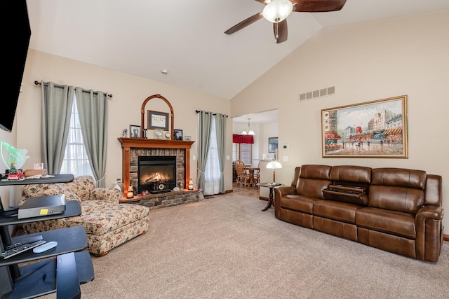 living area featuring high vaulted ceiling, carpet, ceiling fan, visible vents, and a stone fireplace