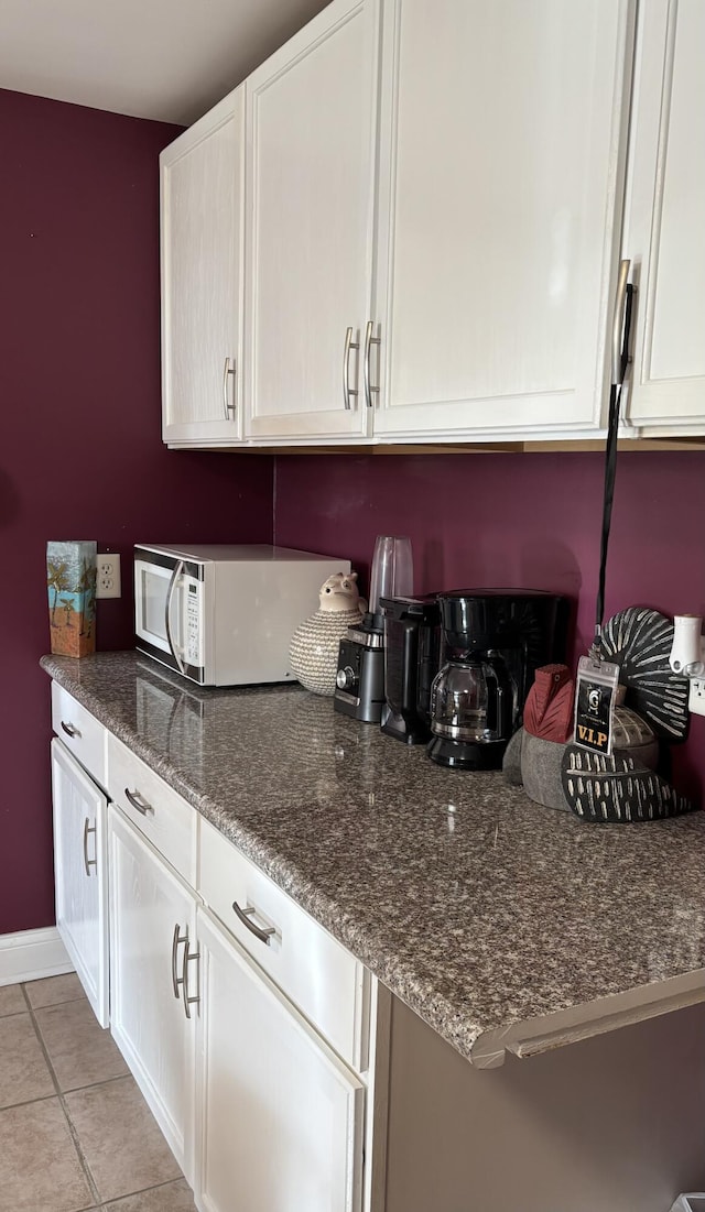98 S Main St, Dry Ridge, KY 41035 - kitchen featuring dark stone countertops, light tile patterned floors, baseboards, white cabinets, and white microwave
