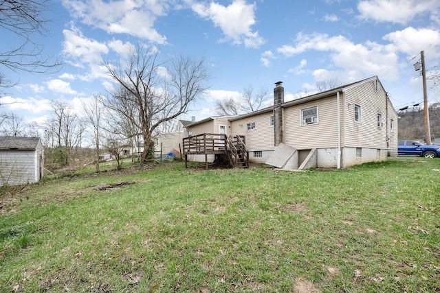 rear view of property featuring an outdoor structure, a chimney, a yard, and a wooden deck