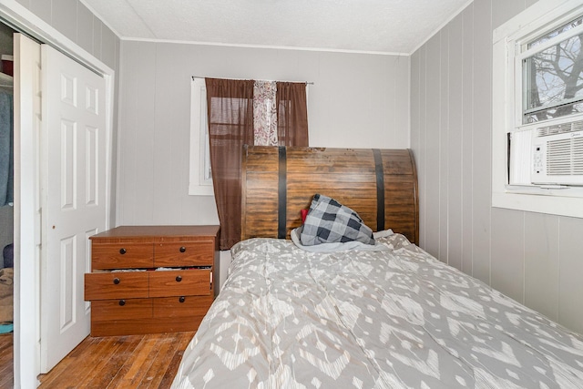 bedroom with cooling unit, crown molding, and wood finished floors