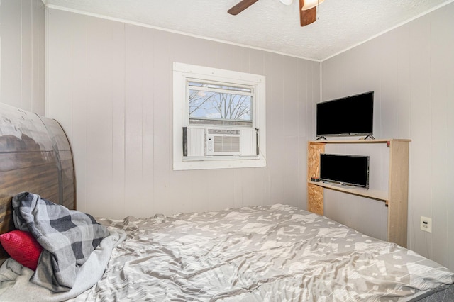bedroom featuring cooling unit, ceiling fan, ornamental molding, and a textured ceiling