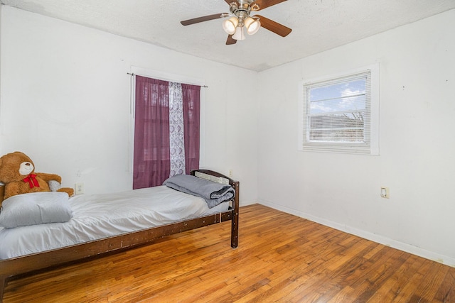bedroom with baseboards, ceiling fan, hardwood / wood-style flooring, and a textured ceiling
