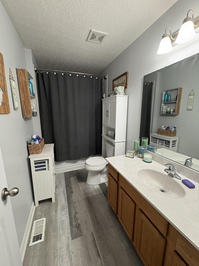 full bathroom featuring vanity, visible vents, a shower with curtain, and wood finished floors