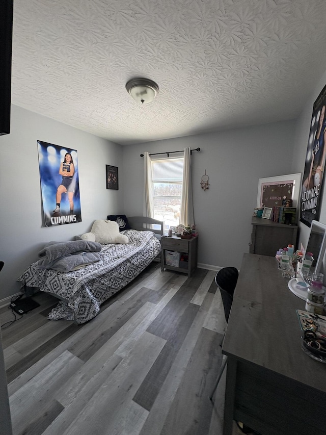 bedroom with a textured ceiling, wood finished floors, and baseboards