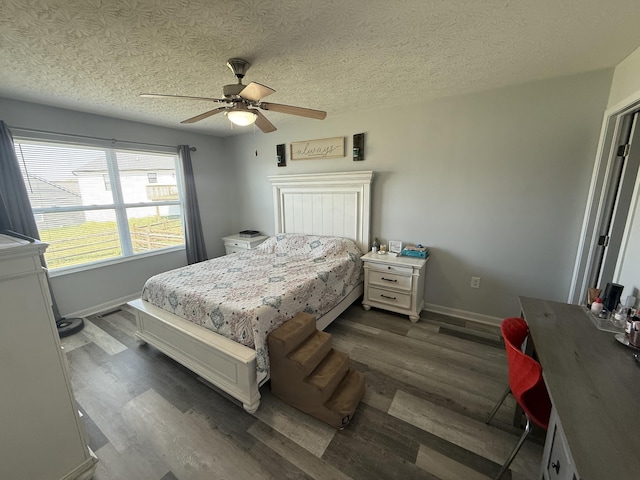 bedroom featuring dark wood-style flooring, baseboards, a ceiling fan, and a textured ceiling