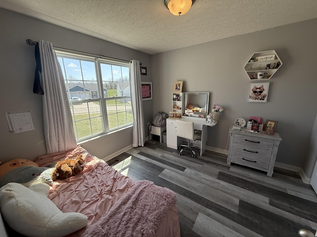 bedroom featuring baseboards, a textured ceiling, and wood finished floors