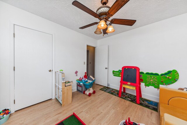 game room with a textured ceiling, wood finished floors, and ceiling fan