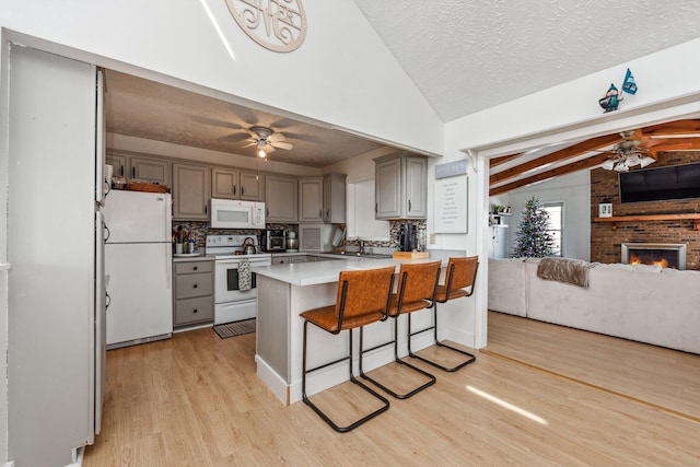 kitchen with a peninsula, vaulted ceiling with beams, ceiling fan, and white appliances