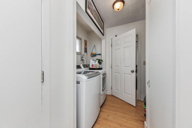 washroom with a textured ceiling, light wood-style flooring, independent washer and dryer, and laundry area