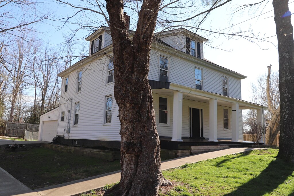 traditional style home with covered porch, a garage, and a front lawn