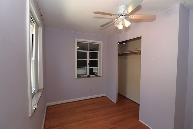 unfurnished bedroom featuring baseboards, a ceiling fan, wood finished floors, and a closet