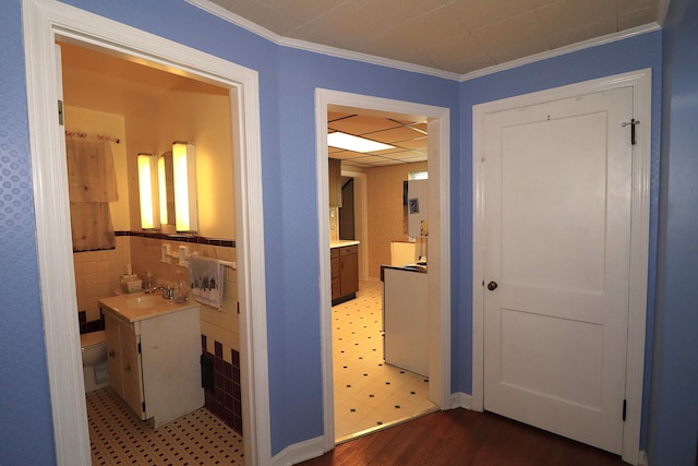 hallway featuring light wood-type flooring, crown molding, and a sink