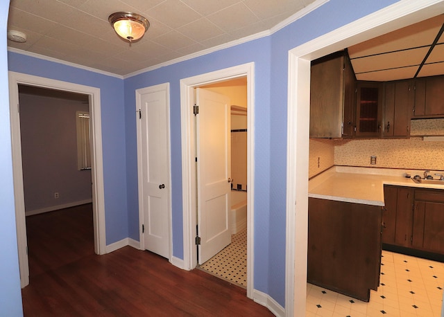 kitchen featuring baseboards, crown molding, light wood-style flooring, and light countertops