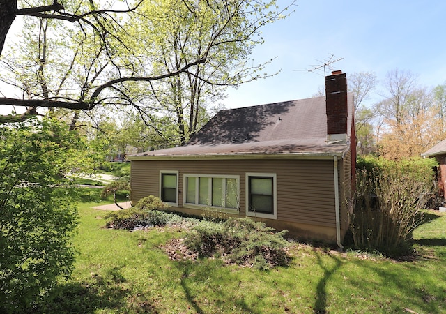 view of side of home with a yard and a chimney