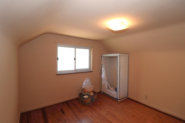bonus room with lofted ceiling, baseboards, and wood finished floors