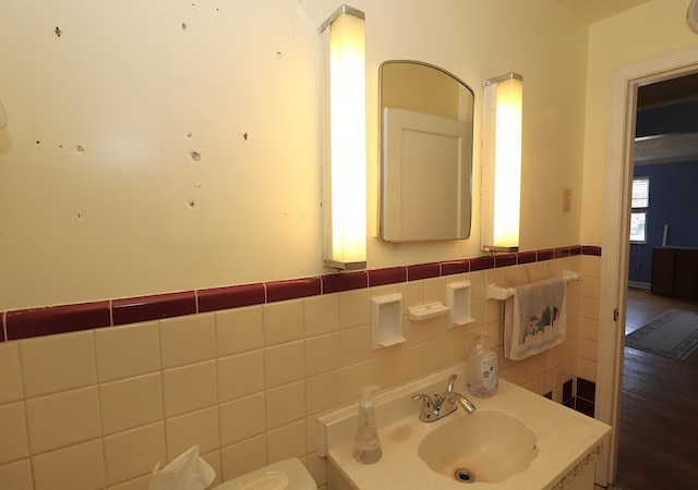 bathroom with tile walls, wainscoting, and a sink